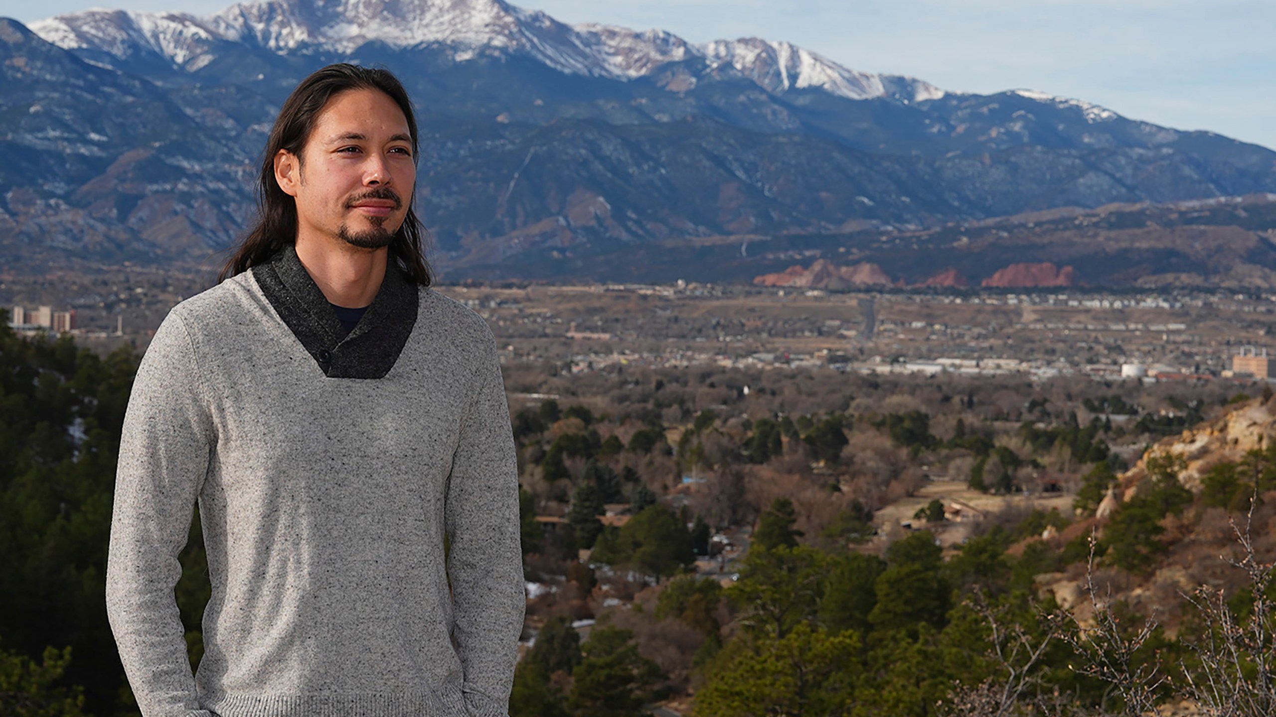 Lane Belone poses with Pikes Peak in the background on an overlook in Palmer Park, Thursday, Dec. 19, 2024, in Colorado Springs, Colo. (AP Photo/David Zalubowski)