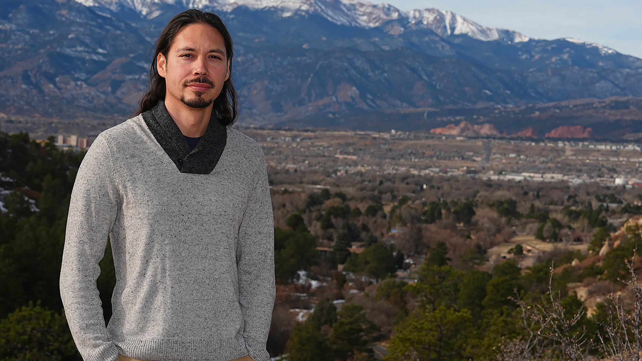 Lane Belone poses with Pikes Peak in the background on an overlook in Palmer Park, Thursday, Dec. 19, 2024, in Colorado Springs, Colo. (AP Photo/David Zalubowski)