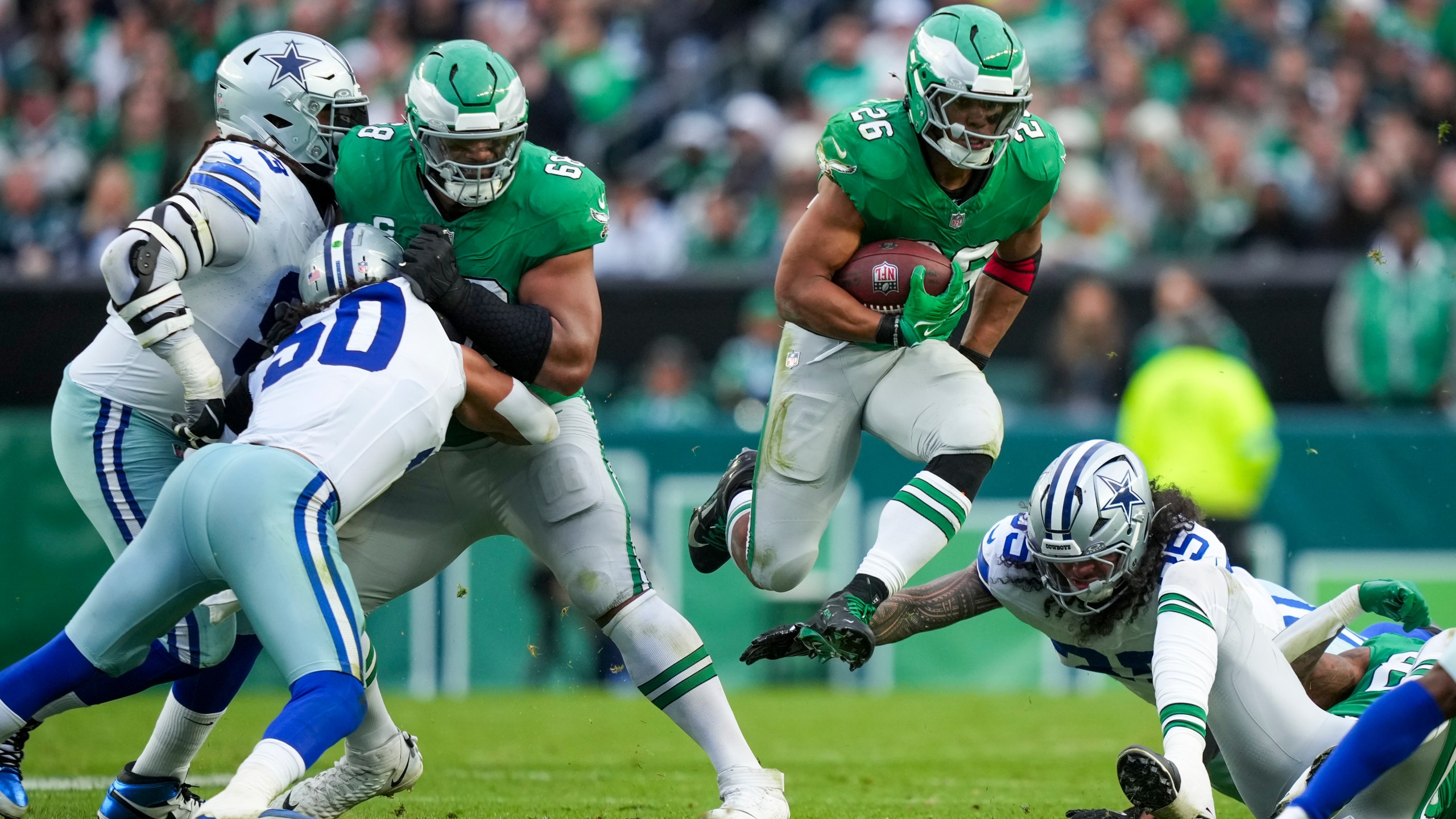 Philadelphia Eagles running back Saquon Barkley, center, leaps as Dallas Cowboys linebacker Marist Liufau tries to trip him up during the second half of an NFL football game, Sunday, Dec. 29, 2024, in Philadelphia. (AP Photo/Matt Slocum)