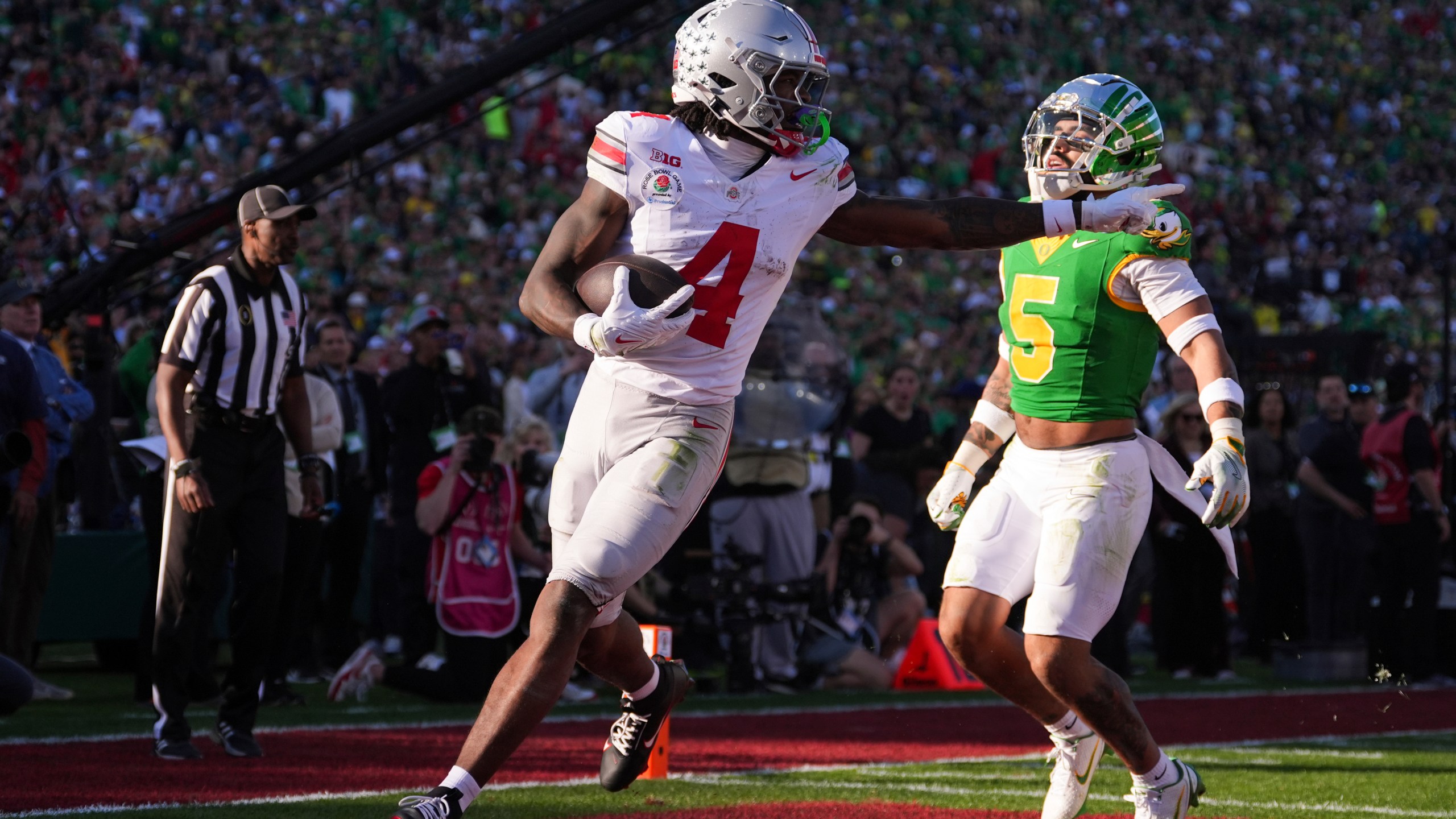 Ohio State wide receiver Jeremiah Smith (4) gestures as he scores a touchdown against Oregon defensive back Kobe Savage (5) during the first half in the quarterfinals of the Rose Bowl College Football Playoff, Wednesday, Jan. 1, 2025, in Pasadena, Calif. (AP Photo/Mark J. Terrill)