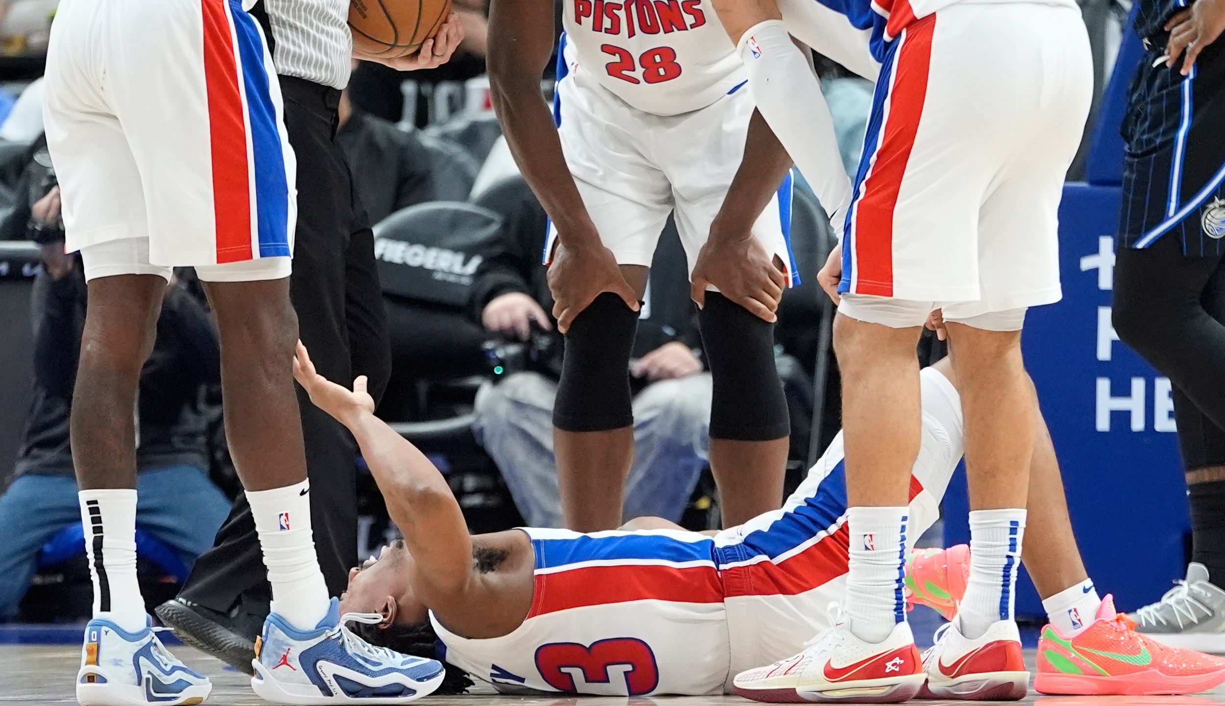 Teammates look over Detroit Pistons guard Jaden Ivey (23) after an incident during the second half of an NBA basketball game against the Orlando Magic, Wednesday, Jan. 1, 2025, in Detroit. Ivey was carted off the court by stretcher. (AP Photo/Carlos Osorio)