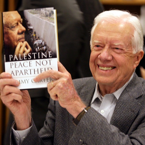 FILE - Former President Jimmy Carter holds a copy of his book, "Palestine: Peace, Not Apartheid," prior to a book signing at the Changing Hands bookstore on Dec. 12, 2006, in Tempe, Ariz. (AP Photo/Paul Connors, File)