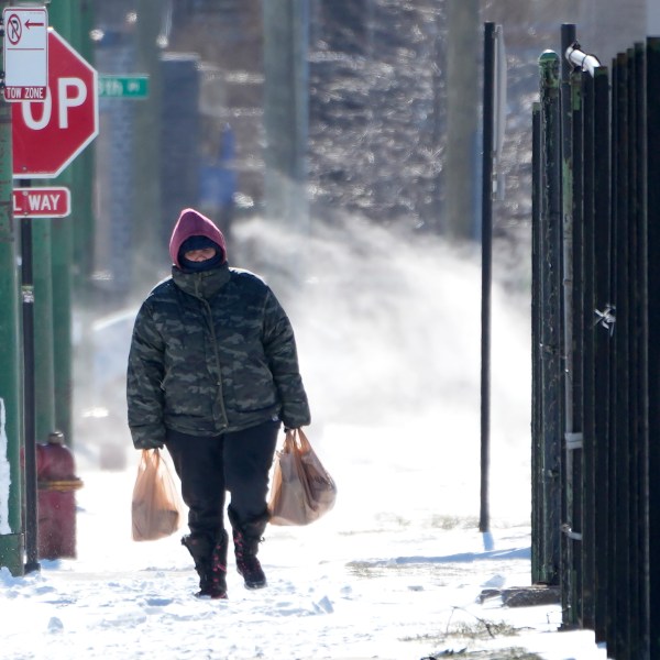 FILE - A person walk almost a half mile to their home from a grocery store as steam from an underground vent rises behind them in the Bronzeville neighborhood of Chicago, Tuesday, Jan. 16, 2024. (AP Photo/Charles Rex Arbogast, File)