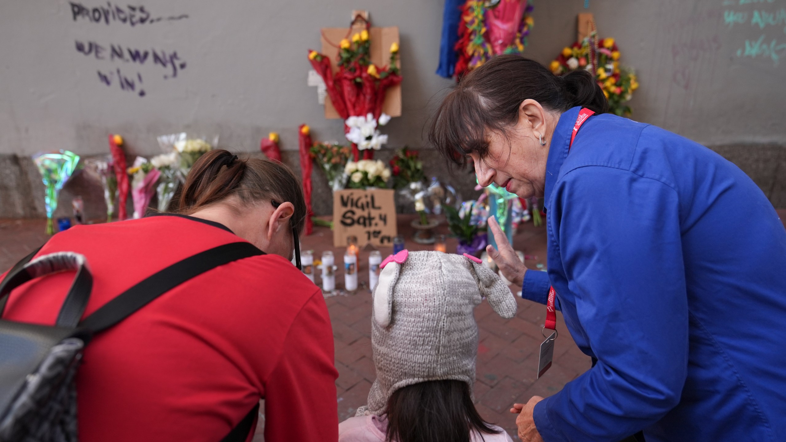 Allyson Tomkins, right, prays with Emily Lara, 5, center, and her grandmother Charity Lara, right, at a memorial to the victims of a deadly truck attack on Bourbon Street in the French Quarter, Friday, Jan. 3, 2025, in New Orleans. (AP Photo/George Walker IV)