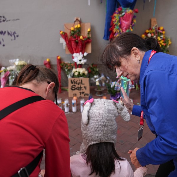 Allyson Tomkins, right, prays with Emily Lara, 5, center, and her grandmother Charity Lara, right, at a memorial to the victims of a deadly truck attack on Bourbon Street in the French Quarter, Friday, Jan. 3, 2025, in New Orleans. (AP Photo/George Walker IV)