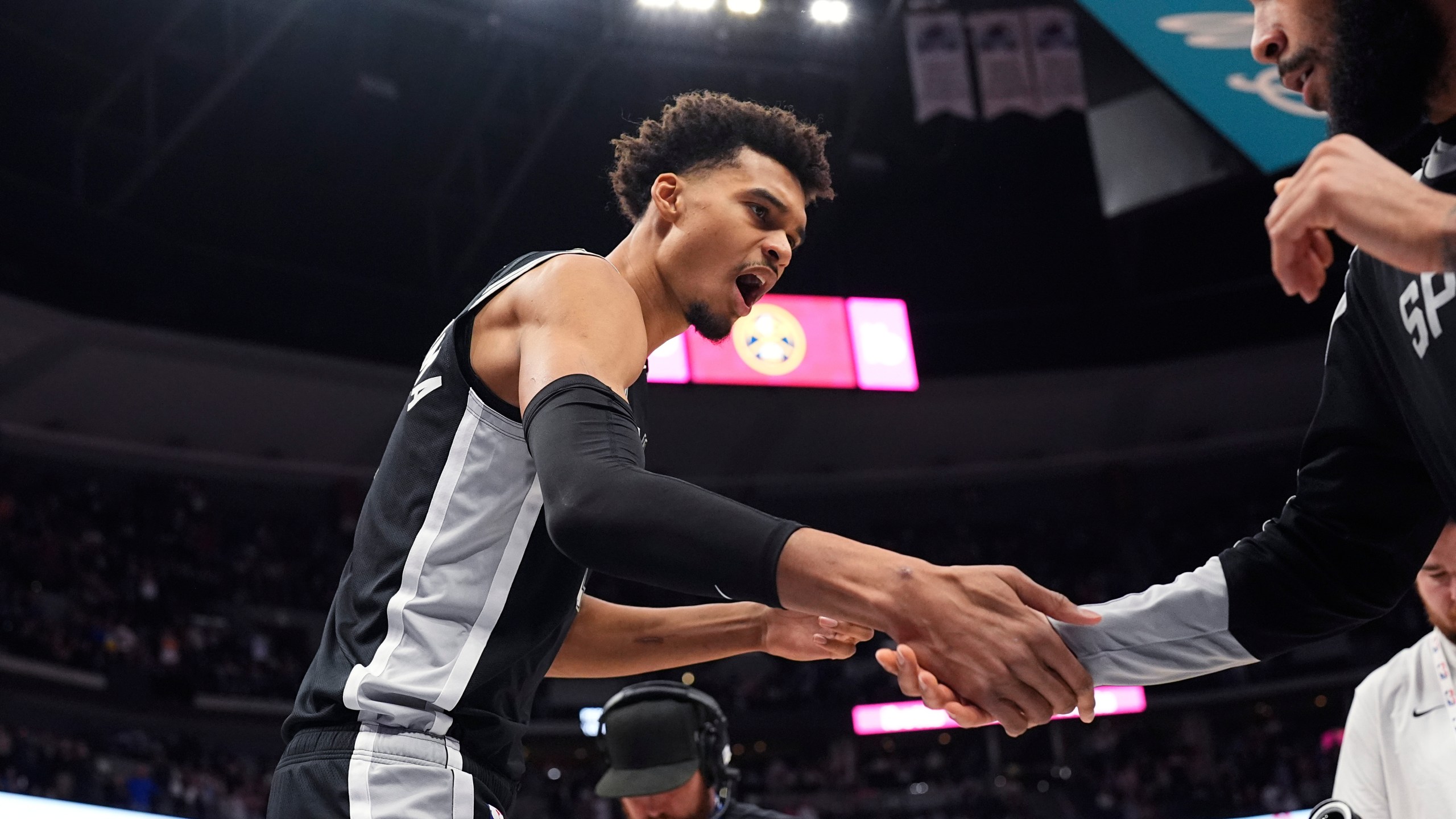 San Antonio Spurs center Victor Wembanyama, left, greets forward Julian Champagnie, right, while taking the court for an NBA basketball game against the Denver Nuggets, Friday, Jan. 3, 2025, in Denver. (AP Photo/David Zalubowski)