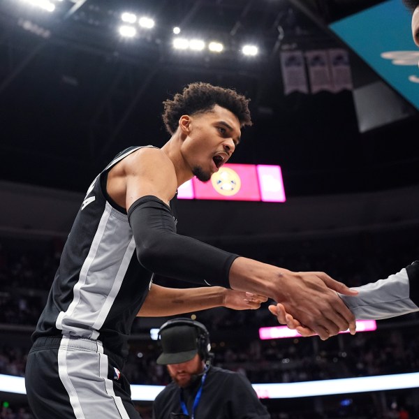 San Antonio Spurs center Victor Wembanyama, left, greets forward Julian Champagnie, right, while taking the court for an NBA basketball game against the Denver Nuggets, Friday, Jan. 3, 2025, in Denver. (AP Photo/David Zalubowski)