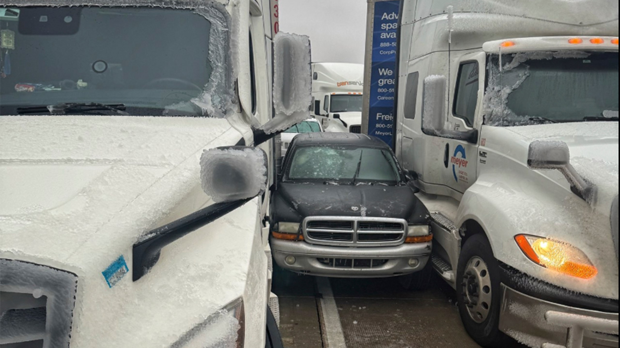 In a photo released by the Kansas Highway Patrol, a car is wedged between two trucks during icy weather Saturday, Jan. 4, 2024, in Salina, Kansas. (Kansas Highway Patrol via AP)