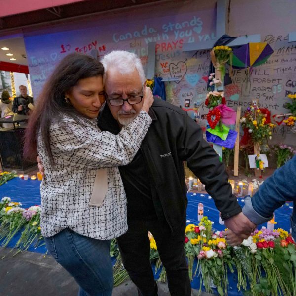 Long Island, New York residents Louis Tenedorio is hugged by family friend Angelique Whittington, left, while holding the hand of his wife, Cathy Tenedorio, by a memorial Bourbon Street and Canal Street in New Orleans, Saturday, Jan. 4, 2025, where their son, Matthew Tenedorio, was killed as one of the victims of the New Year's Day deadly truck attack and shooting. (AP Photo/Matthew Hinton)