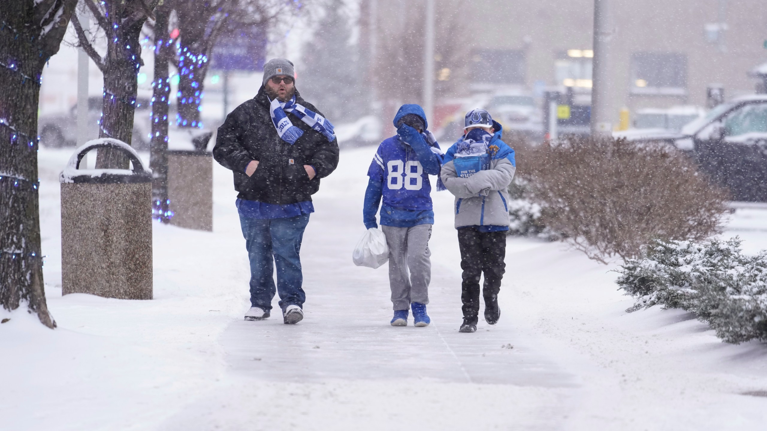 Indianapolis Colts fans walk in the falling snow after an NFL football game between the Colts and the Jacksonville Jaguars, Sunday, Jan. 5, 2025, in Indianapolis. (AP Photo/Michael Conroy)