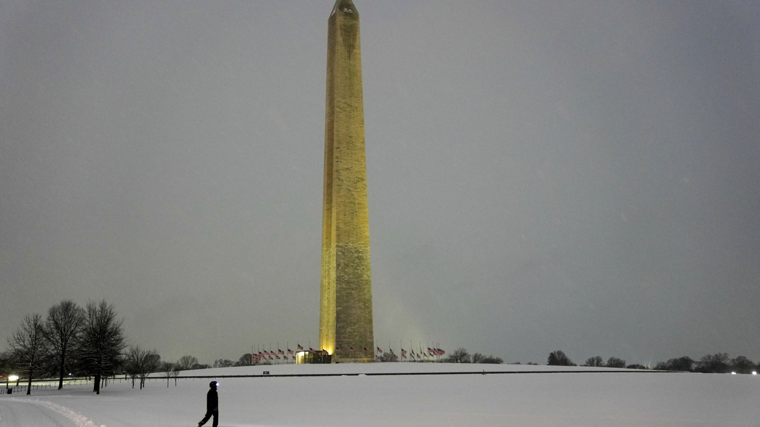 A person walks near the Washington Monument during a winter snow storm in Washington, Monday, Jan. 6, 2025. (AP Photo/Matt Rourke)