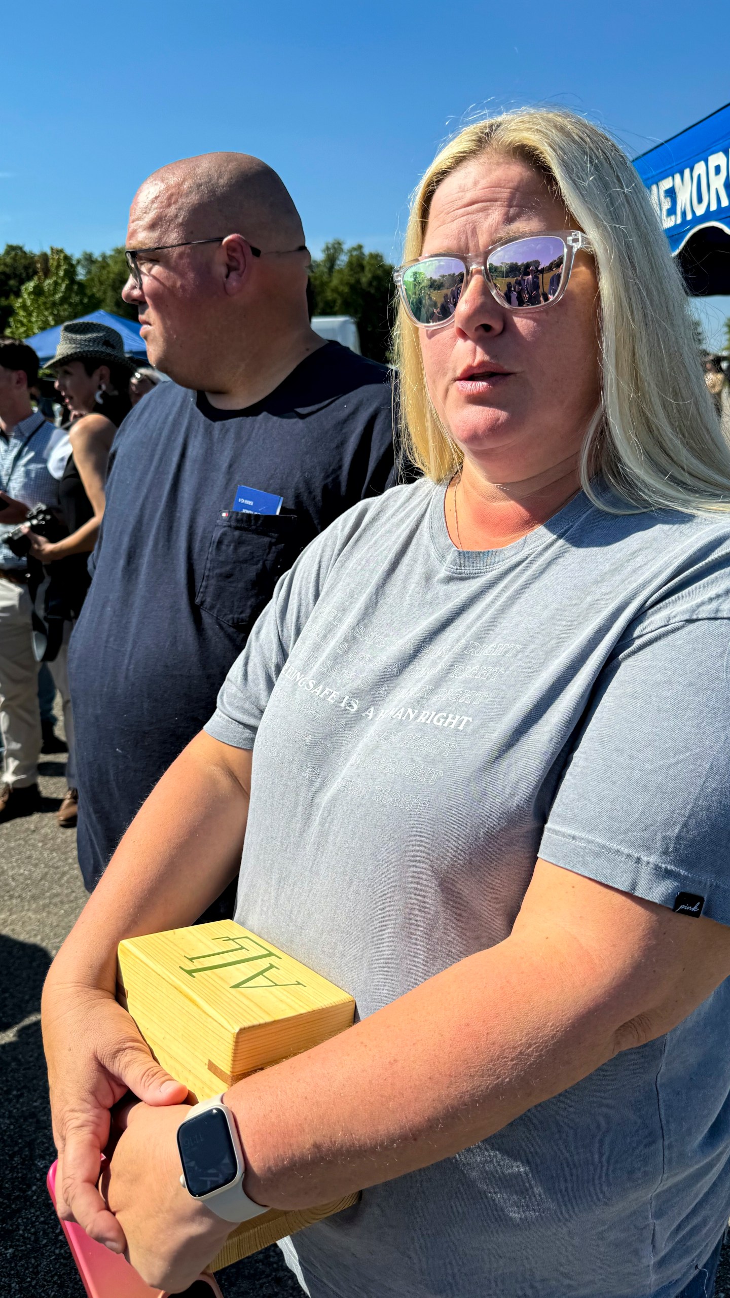 Shannon Doughty stands in front of her husband, Matt, while holding a wooden box on Aug. 29, 2024, in Westfield, Indiana, that had contained some of the cremated remains of her late brother Allen Livingston, who was identified in October 2023 as the ninth known victim of suspected serial killer Herbert Baumeister. (AP Photo/Rick Callahan)