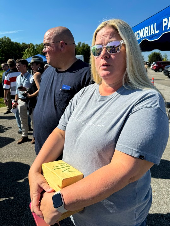 Shannon Doughty stands in front of her husband, Matt, while holding a wooden box on Aug. 29, 2024, in Westfield, Indiana, that had contained some of the cremated remains of her late brother Allen Livingston, who was identified in October 2023 as the ninth known victim of suspected serial killer Herbert Baumeister. (AP Photo/Rick Callahan)