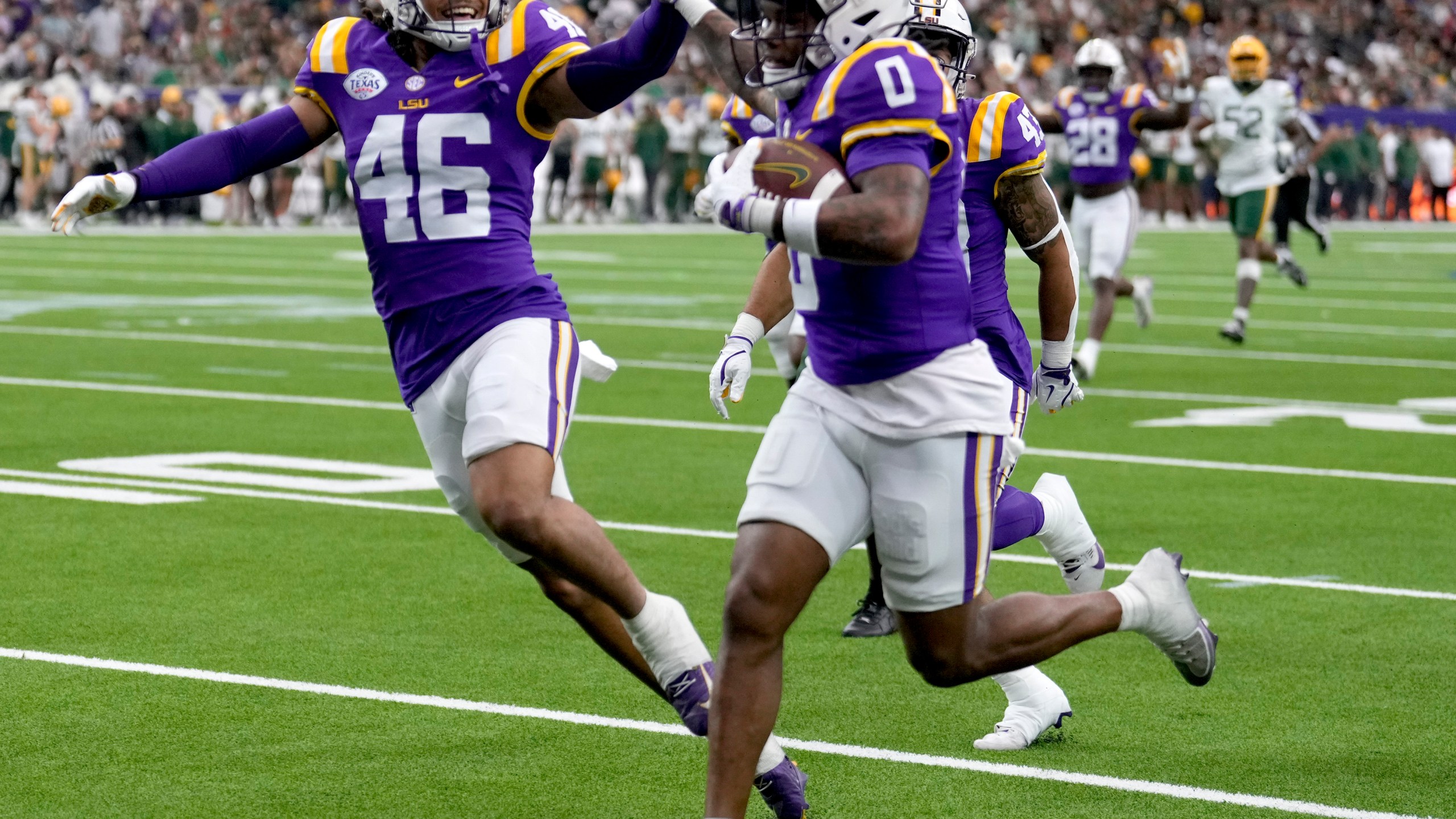 LSU linebacker Tylen Singleton, left, gives wide receiver Zavion Thomas (0) a high-five as Thomas returns a kickoff for a touchdown against Baylor during the first half of the Texas Bowl NCAA college football game Tuesday, Dec. 31, 2024, in Houston. (Brett Coomer/Houston Chronicle via AP)