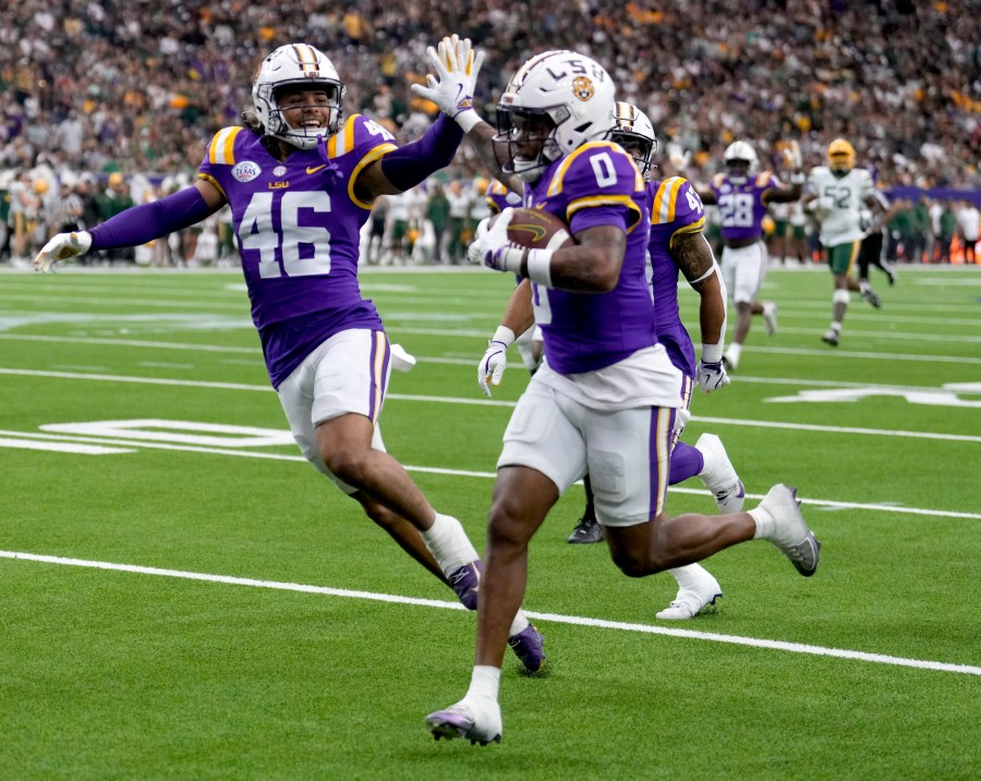 LSU linebacker Tylen Singleton, left, gives wide receiver Zavion Thomas (0) a high-five as Thomas returns a kickoff for a touchdown against Baylor during the first half of the Texas Bowl NCAA college football game Tuesday, Dec. 31, 2024, in Houston. (Brett Coomer/Houston Chronicle via AP)