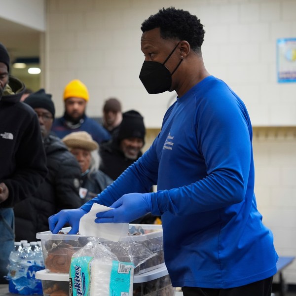 Idris Mills, right, hands out food to patrons inside a daytime warming shelter, Tuesday, Jan. 7, 2025, in Cincinnati. (AP Photo/Joshua A. Bickel)