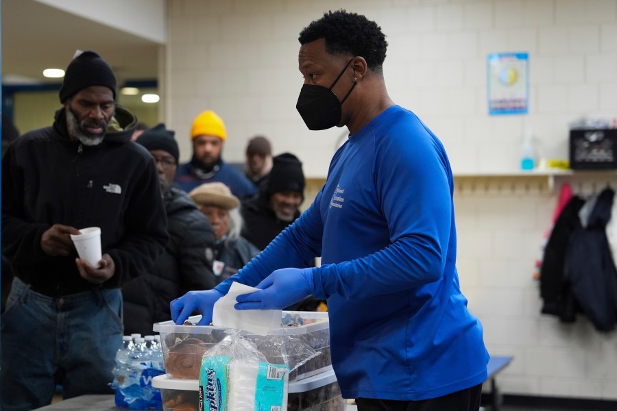 Idris Mills, right, hands out food to patrons inside a daytime warming shelter, Tuesday, Jan. 7, 2025, in Cincinnati. (AP Photo/Joshua A. Bickel)