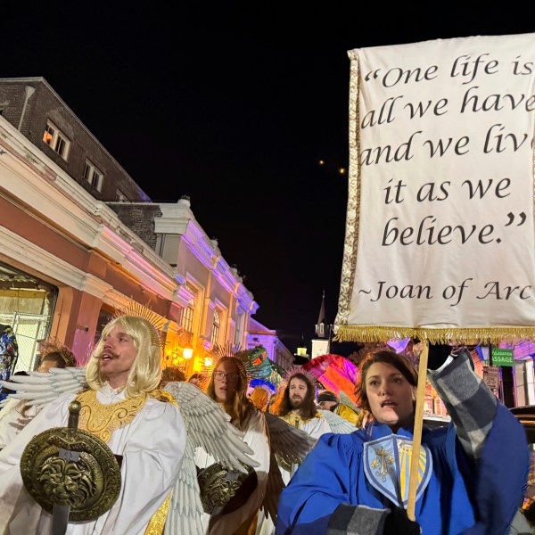 Marchers in the Joan of Arc parade on Monday, Jan. 6, 2025, in New Orleans, hold aloft a banner with a quote from the French saint. (AP Photo/Jack Brook)