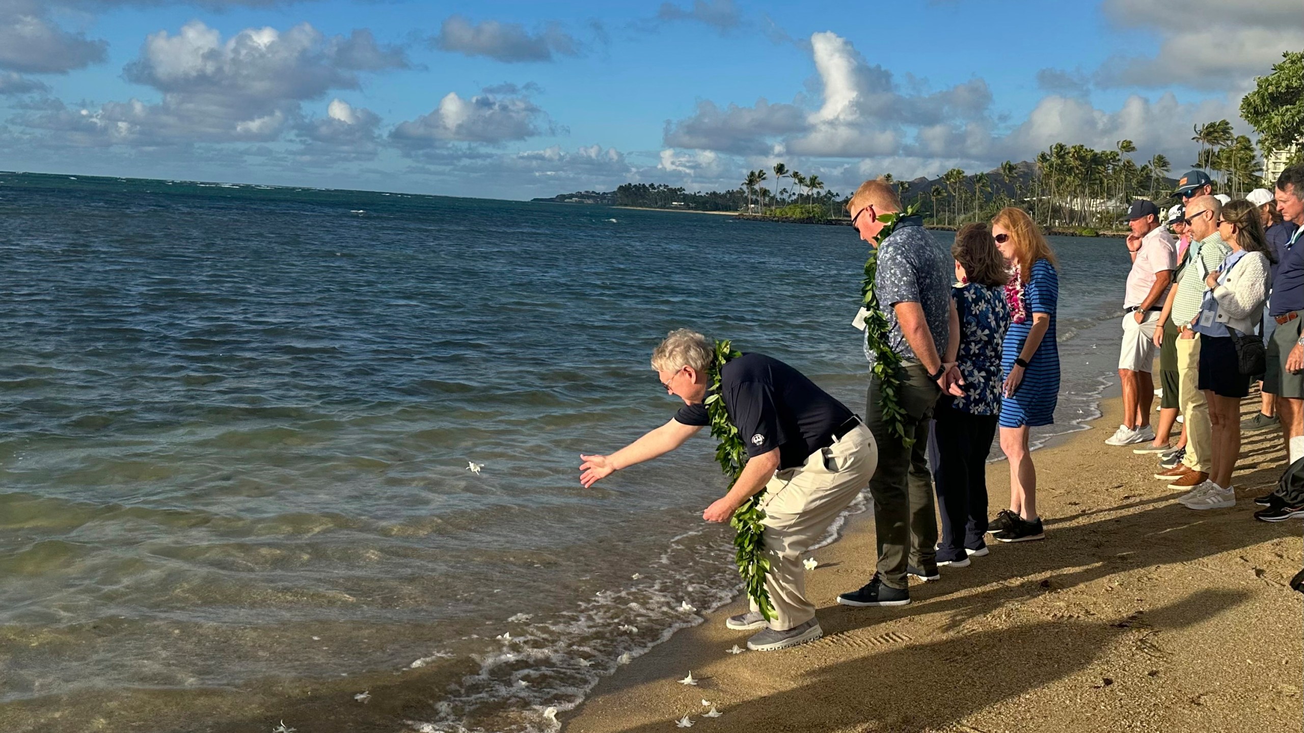 Eric Murray, father of the late PGA Tour player Grayson Murray, tosses a white orchid into the ocean Tuesday, Jan. 7, 2025, during a celebration of life for his son at Waialae Country Club in Honolulu. (AP Photo/Doug Ferguson)