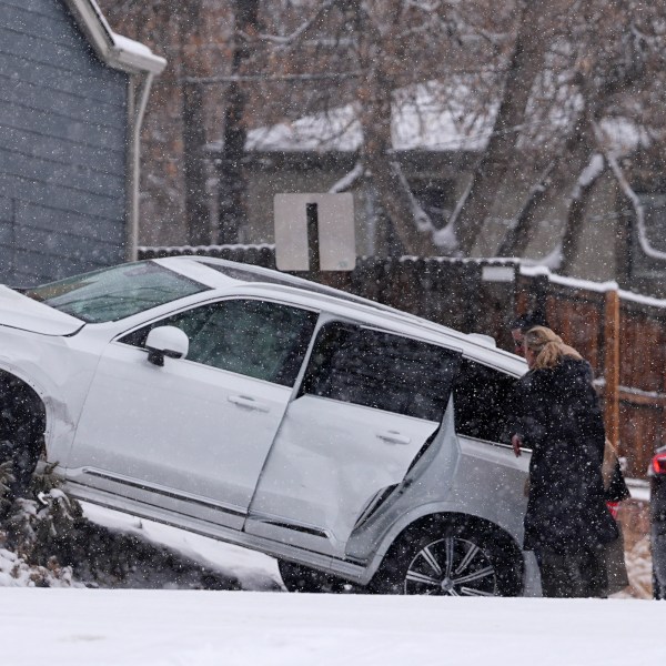 Motorists survey damage done to a utility vehicle in a crash at an intersection as a winter storm sweeps over the intermountain West and across the country Tuesday, Jan. 7, 2025, in southeast Denver. (AP Photo/David Zalubowski)