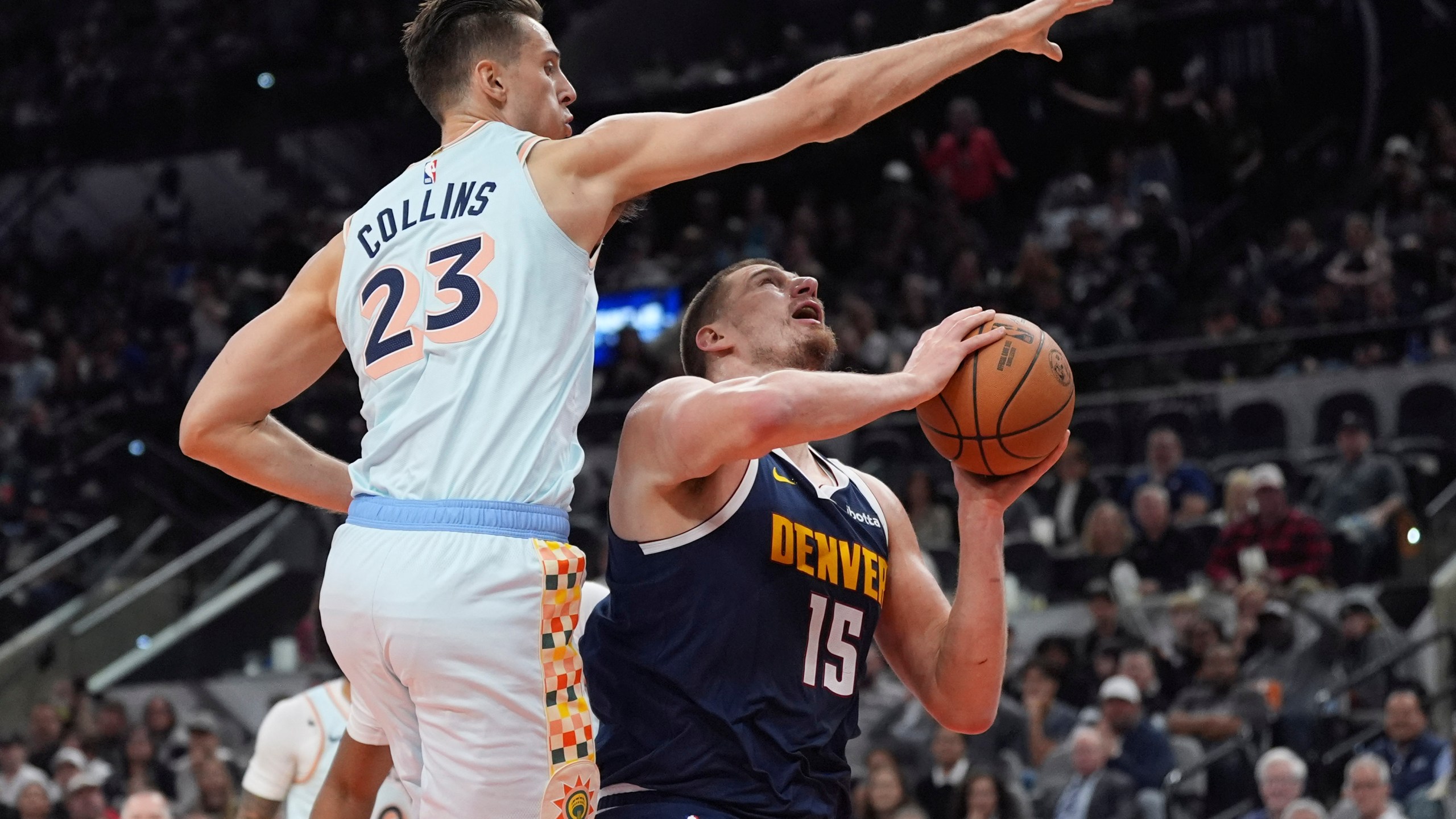 Denver Nuggets center Nikola Jokic (15) drives to the basket against San Antonio Spurs forward Zach Collins (23) during the first half of an NBA basketball game in San Antonio, Saturday, Jan. 4, 2025. (AP Photo/Eric Gay)