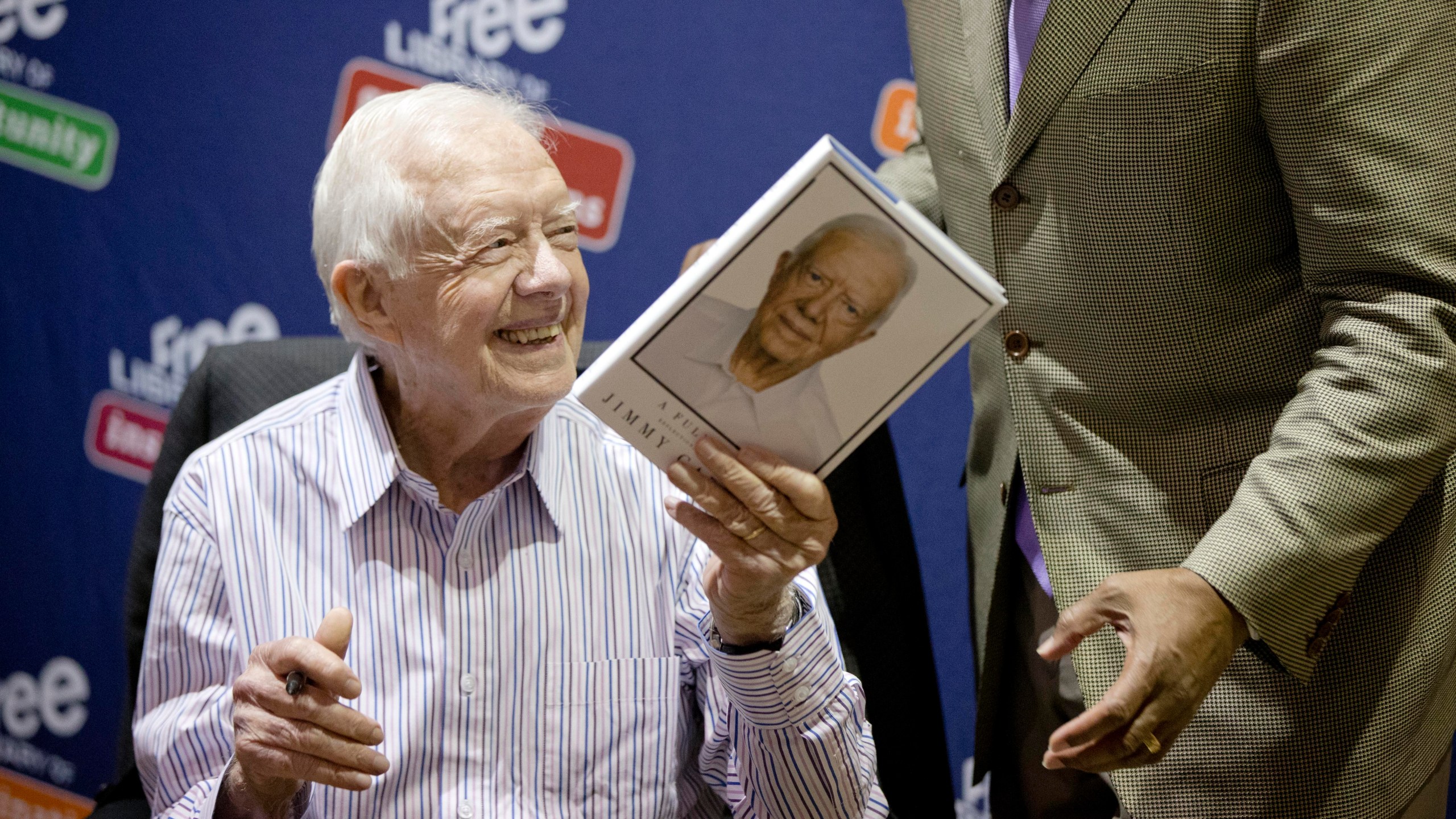 FILE - Former President Jimmy Carter hands a copy of his new book, "A Full Life: Reflections at Ninety," to Philadelphia Mayor Michael Nutter, on July 10, 2015, at the Free Library in Philadelphia. (AP Photo/Matt Rourke, File)