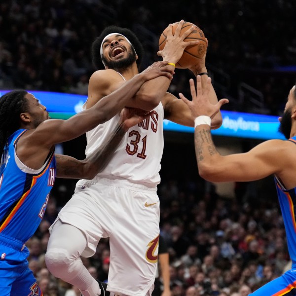 Cleveland Cavaliers center Jarrett Allen (31) is fouled by Oklahoma City Thunder guard Cason Wallace, left, as he drives to the basket between Wallace and Kenrich Williams (34), right, in the first half of an NBA basketball game, Wednesday, Jan. 8, 2025, in Cleveland. (AP Photo/Sue Ogrocki)