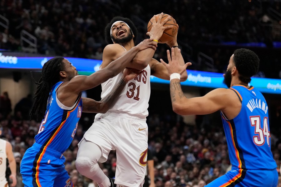 Cleveland Cavaliers center Jarrett Allen (31) is fouled by Oklahoma City Thunder guard Cason Wallace, left, as he drives to the basket between Wallace and Kenrich Williams (34), right, in the first half of an NBA basketball game, Wednesday, Jan. 8, 2025, in Cleveland. (AP Photo/Sue Ogrocki)