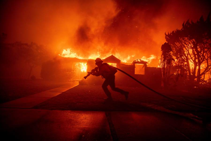 A firefighter battles the Palisades Fire as it burns a structure in the Pacific Palisades neighborhood of Los Angeles, Tuesday, Jan. 7, 2025. (AP Photo/Ethan Swope)