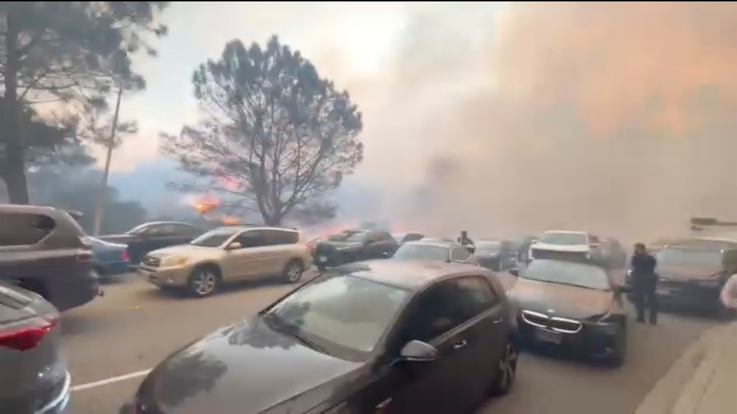 CORRECTS LOCATION TO PACIFIC PALISADES, INSTEAD OF GLENHAVEN - People evacuate their cars as flames from a wildfire spread to the street near Pacific Palisades, Calif., on Tuesday, Jan. 7, 2025. (Aaron Samson via AP)