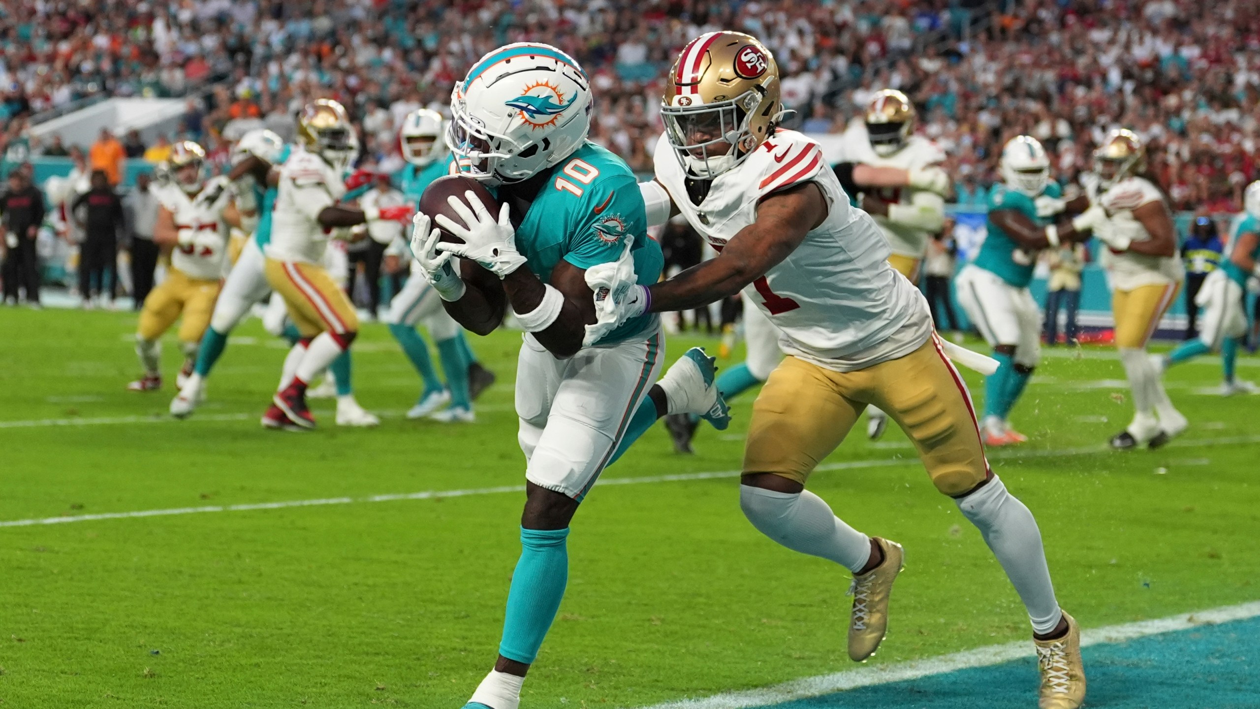 Miami Dolphins wide receiver Tyreek Hill (10) catches a pass for a touchdown as San Francisco 49ers cornerback Charvarius Ward (7) gives him a push during the first half of an NFL football game, Sunday, Dec. 22, 2024, in Miami Gardens, Fla. (AP Photo/Rebecca Blackwell)