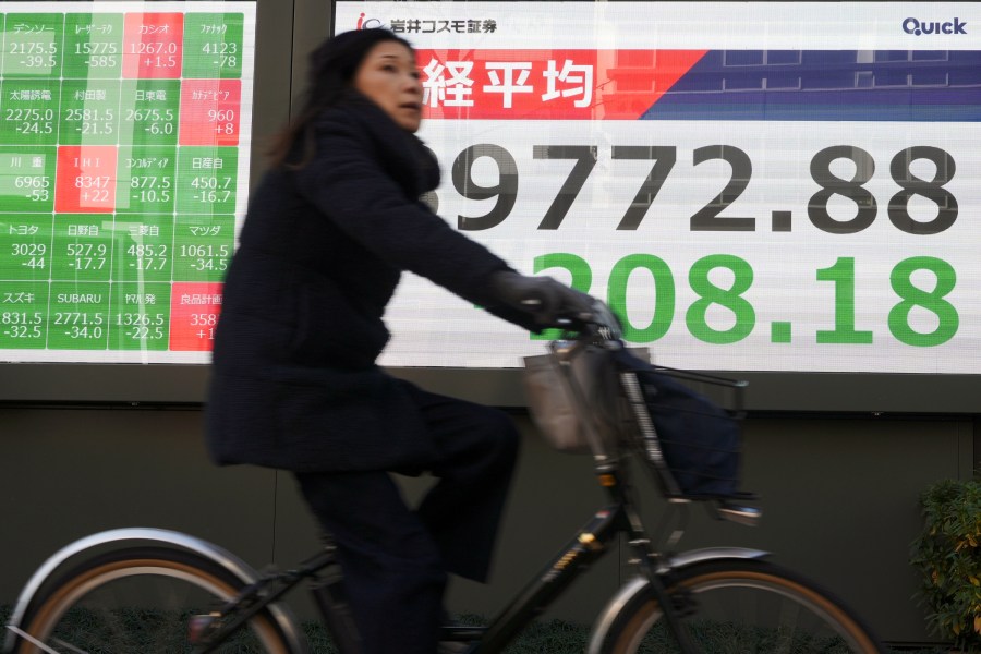 A person rides a bicycle in front of an electronic stock board showing Japan's Nikkei index at a securities firm Thursday, Jan. 9, 2025, in Tokyo. (AP Photo/Eugene Hoshiko)