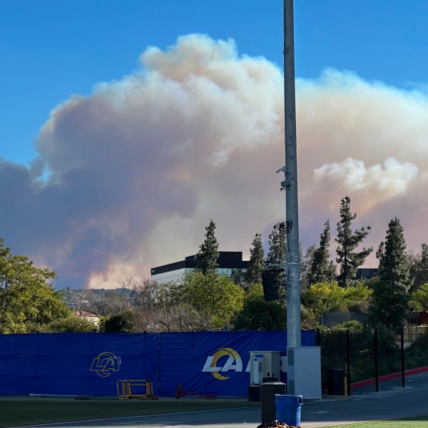 Smokes from a wildfire rises over the Los Angeles Rams NFL football practice facility in the Woodland Hills section of Los Angeles, Thursday, Jan. 9, 2025. (AP Photo/Greg Beacham)