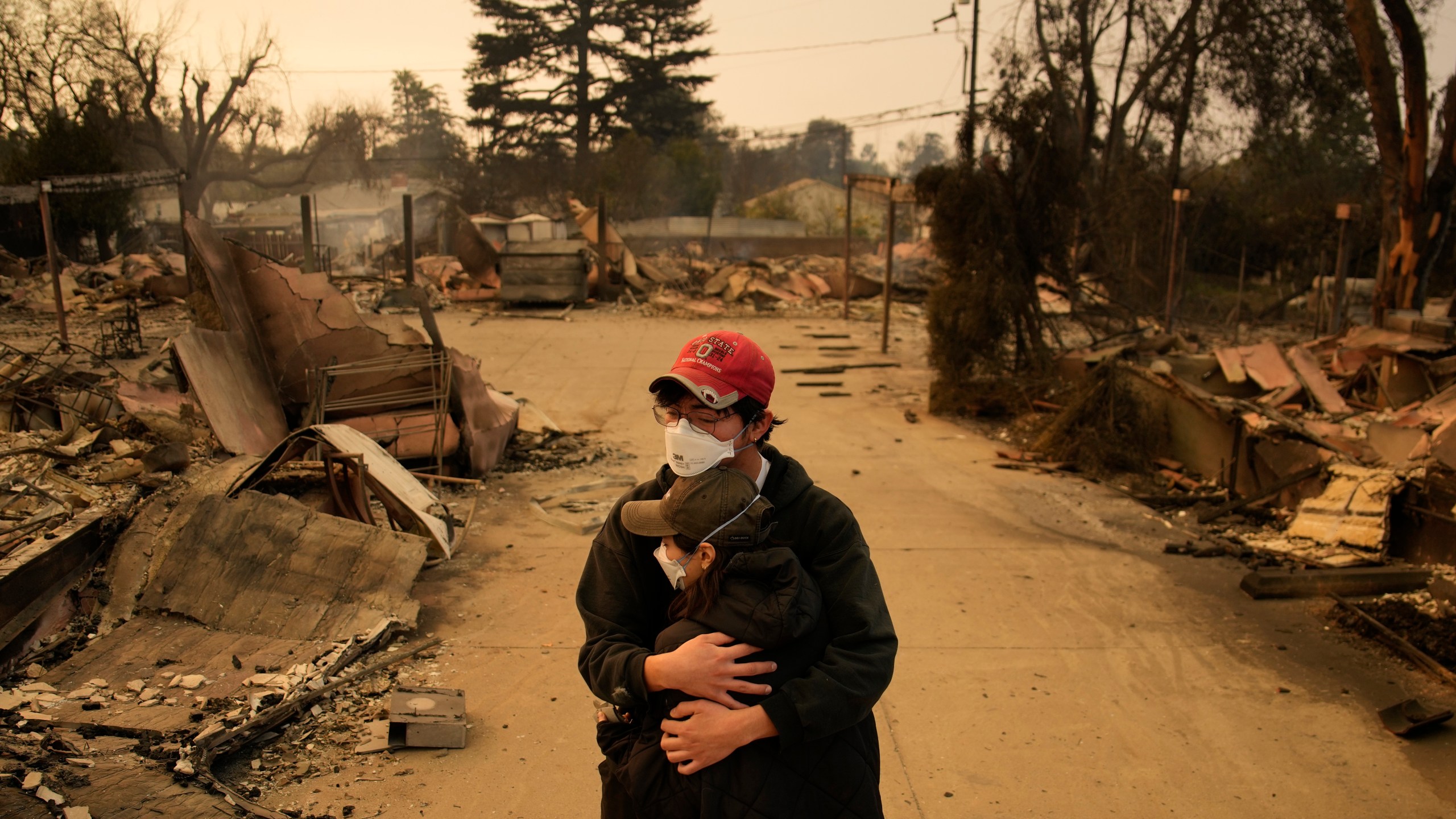 Ari Rivera, rear, Anderson Hao hold each other in front of their destroyed home in Altadena, Calif., Thursday, Jan. 9, 2025. (AP Photo/John Locher)