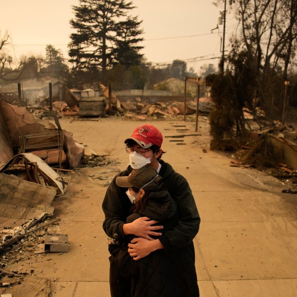 Ari Rivera, rear, Anderson Hao hold each other in front of their destroyed home in Altadena, Calif., Thursday, Jan. 9, 2025. (AP Photo/John Locher)