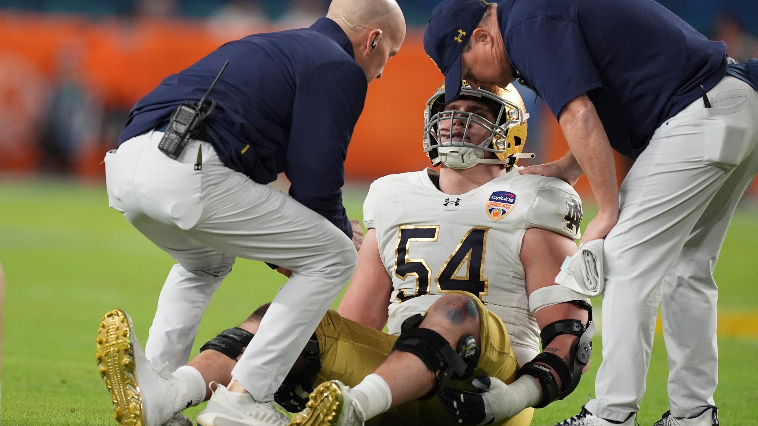 Notre Dame offensive lineman Anthonie Knapp (54) is assisted on the field during the first half of the Orange Bowl NCAA College Football Playoff semifinal game against Penn State, Thursday, Jan. 9, 2025, in Miami Gardens, Fla. (AP Photo/Rebecca Blackwell)