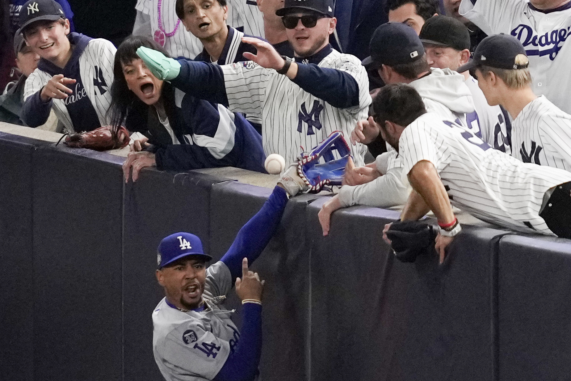 FILE - Fans interfere with a foul ball caught by Los Angeles Dodgers right fielder Mookie Betts during the first inning in Game 4 of the baseball World Series against the New York Yankees, Tuesday, Oct. 29, 2024, in New York. (AP Photo/Ashley Landis, File)