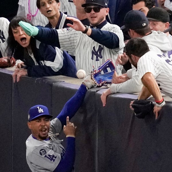 FILE - Fans interfere with a foul ball caught by Los Angeles Dodgers right fielder Mookie Betts during the first inning in Game 4 of the baseball World Series against the New York Yankees, Tuesday, Oct. 29, 2024, in New York. (AP Photo/Ashley Landis, File)