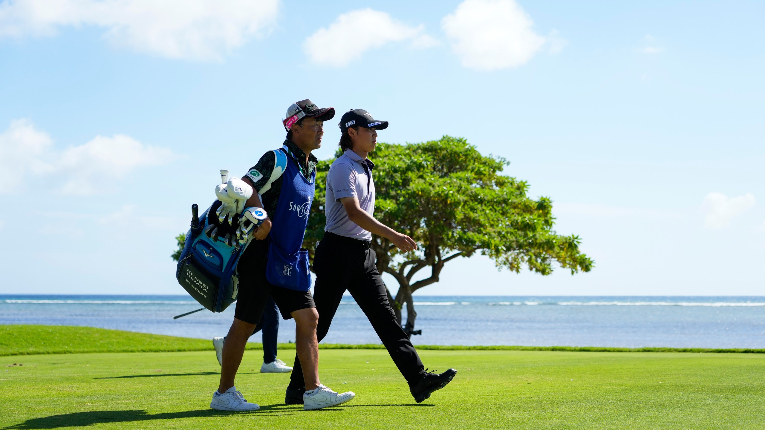 Kensei Hirata, right, of Japan, walks with his caddie on the 17th fairway during the second round of the Sony Open golf event, Friday, Jan. 10, 2025, at Waialae Country Club in Honolulu. (AP Photo/Matt York)