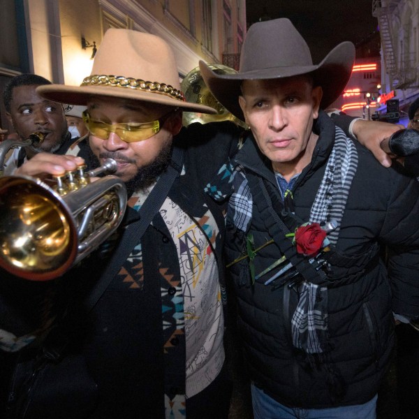 Amir "Tubad" Gray, left, leads Tubad and the Kings of NOLA Brass Band and artist Roberto Marquez, right, in New Orleans, Saturday, Jan. 4, 2025, as they memorialize the victims of the New Year's Day deadly truck attack and shooting. Marquez organized the parade and vigil and designed a memorial for the victims on Bourbon Street. (AP Photo/Matthew Hinton)