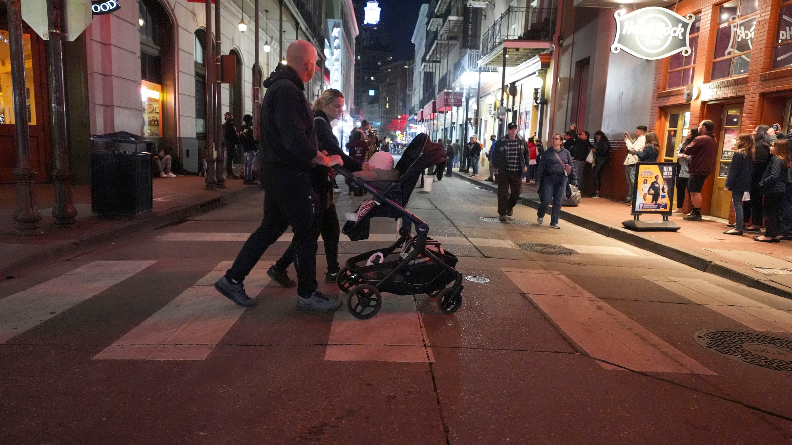 A couple pushes a child in a stroller on Bourbon Street at the site of a deadly truck attack on New Year's Day in New Orleans, Friday, Jan. 3, 2025. (AP Photo/Gerald Herbert)