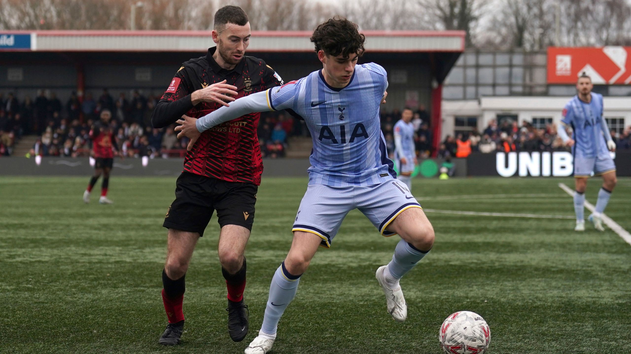 Tamworth's Thomas McLinchey, left, and Tottenham Hotspur's Archie Gray battle for the ball during the English FA Cup third round match at The Lamb Ground, Tamworth, England, Sunday Jan. 12, 2025. (Joe Giddens/PA via AP)