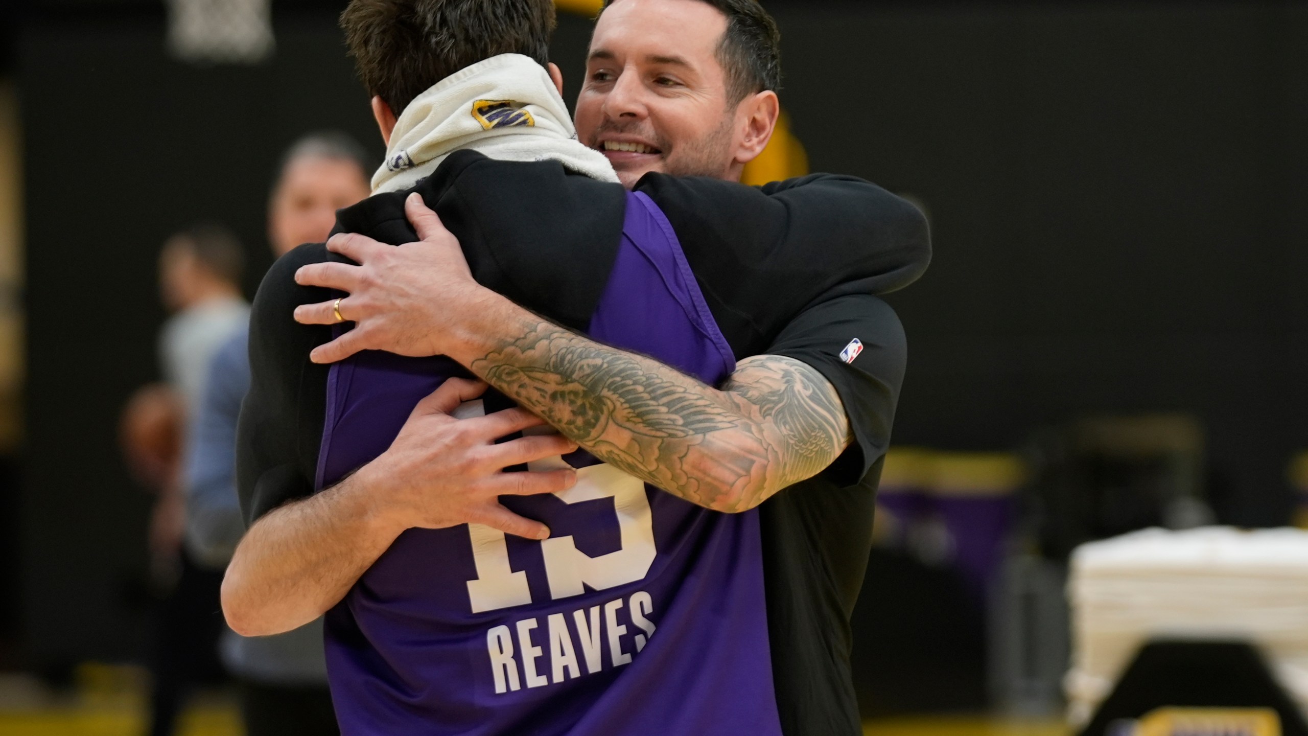 Los Angeles Lakers NBA basketball head coach JJ Redick, right, is hugged by guard Austin Reaves, left before talking to the media about the Pacific Palisades wildfire at a news conference in El Segundo, Calif., Friday, Jan. 10, 2025. (AP Photo/Damian Dovarganes)