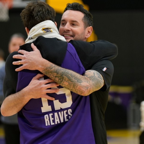 Los Angeles Lakers NBA basketball head coach JJ Redick, right, is hugged by guard Austin Reaves, left before talking to the media about the Pacific Palisades wildfire at a news conference in El Segundo, Calif., Friday, Jan. 10, 2025. (AP Photo/Damian Dovarganes)