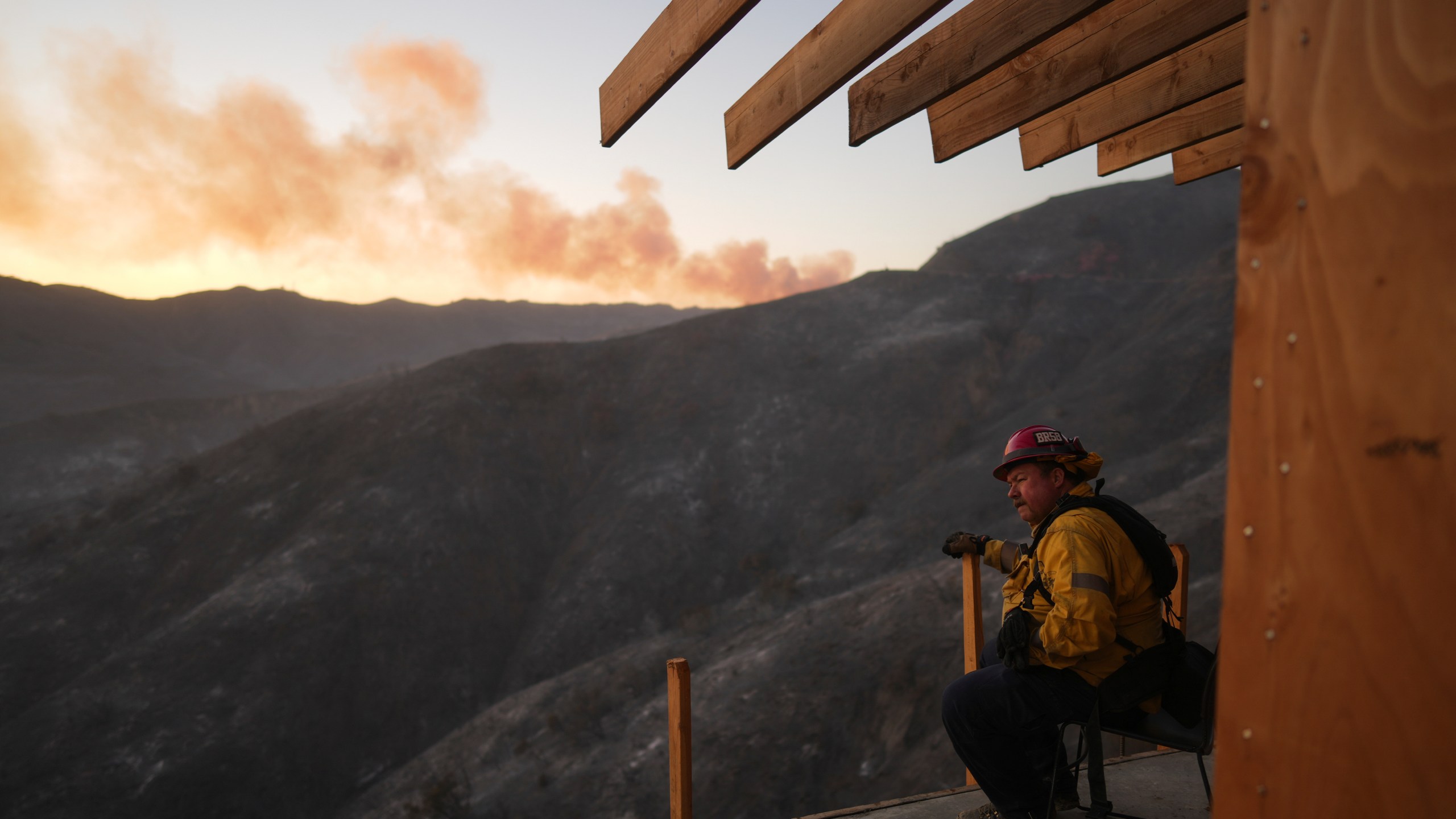 A firefighter rests as crews battle the Palisades Fire in Mandeville Canyon, Saturday, Jan. 11, 2025, in Los Angeles. (AP Photo/Eric Thayer)