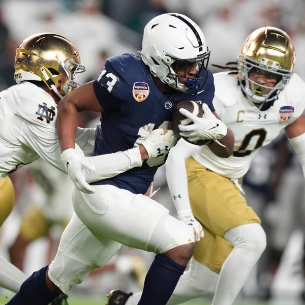 Notre Dame cornerback Leonard Moore (15) grabs Penn State running back Kaytron Allen (13) during the first half of the Orange Bowl NCAA College Football Playoff semifinal game, Thursday, Jan. 9, 2025, in Miami Gardens, Fla. (AP Photo/Rebecca Blackwell)