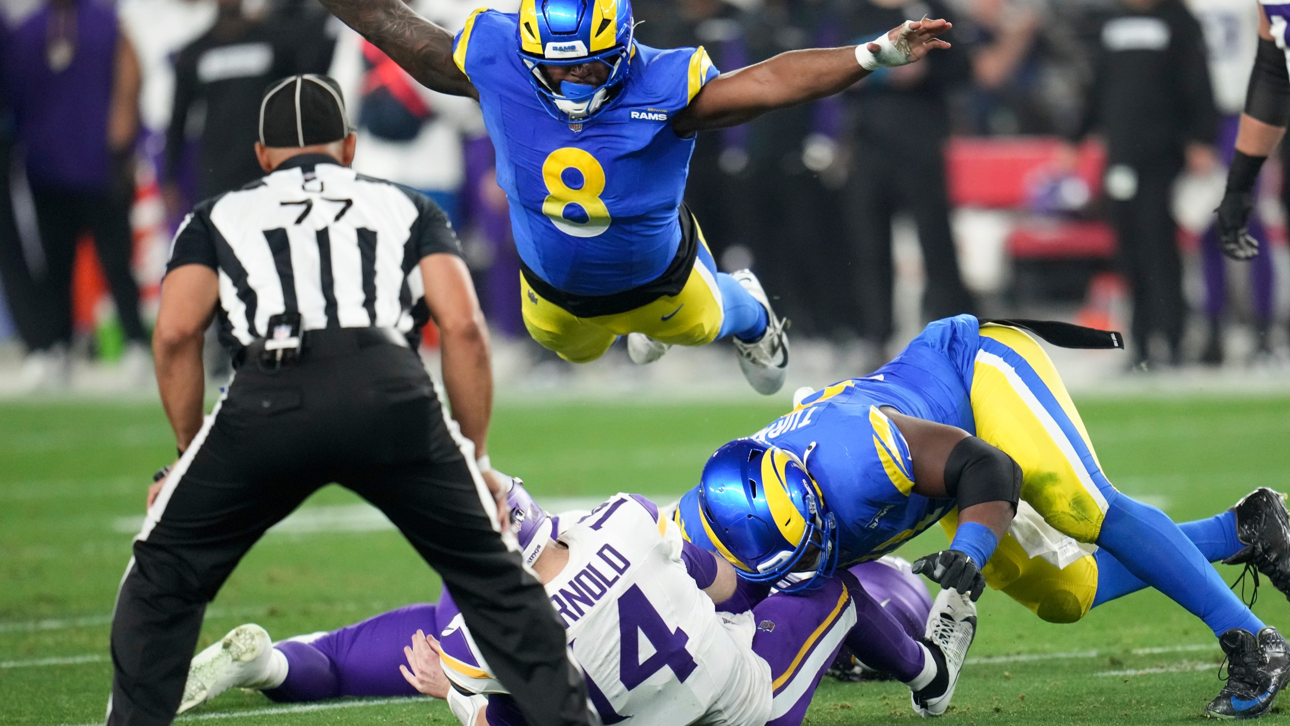 Minnesota Vikings quarterback Sam Darnold (14) is sacked by Los Angeles Rams defensive tackle Kobie Turner (91) as Jared Verse (8) dives on during the first half of an NFL wild card playoff football game, Monday, Jan. 13, 2025, in Glendale, Ariz. (AP Photo/Ross D. Franklin)