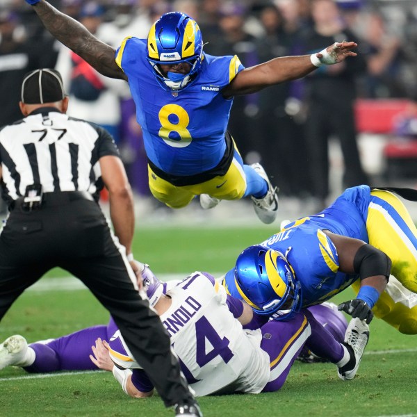 Minnesota Vikings quarterback Sam Darnold (14) is sacked by Los Angeles Rams defensive tackle Kobie Turner (91) as Jared Verse (8) dives on during the first half of an NFL wild card playoff football game, Monday, Jan. 13, 2025, in Glendale, Ariz. (AP Photo/Ross D. Franklin)