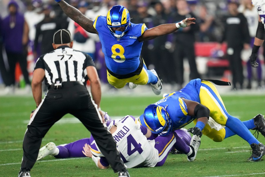 Minnesota Vikings quarterback Sam Darnold (14) is sacked by Los Angeles Rams defensive tackle Kobie Turner (91) as Jared Verse (8) dives on during the first half of an NFL wild card playoff football game, Monday, Jan. 13, 2025, in Glendale, Ariz. (AP Photo/Ross D. Franklin)