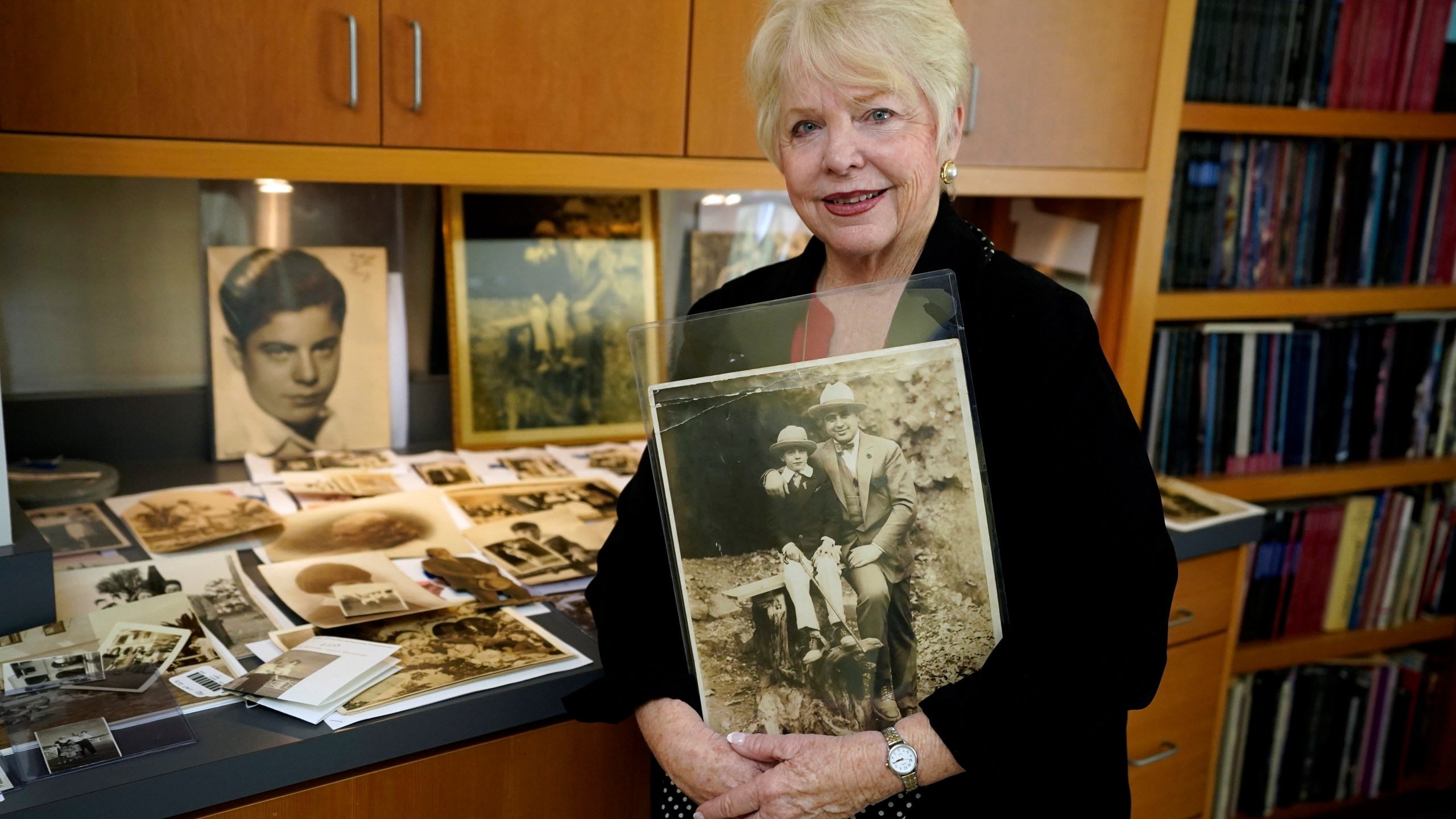 FILE - Diane Capone holds a copy of a photograph of her father, Albert "Sonny" Capone as a young boy and her grandfather Al Capone on display at Witherell's Auction House in Sacramento, Calif., Wednesday, Aug. 25, 2021. (AP Photo/Rich Pedroncelli, File)